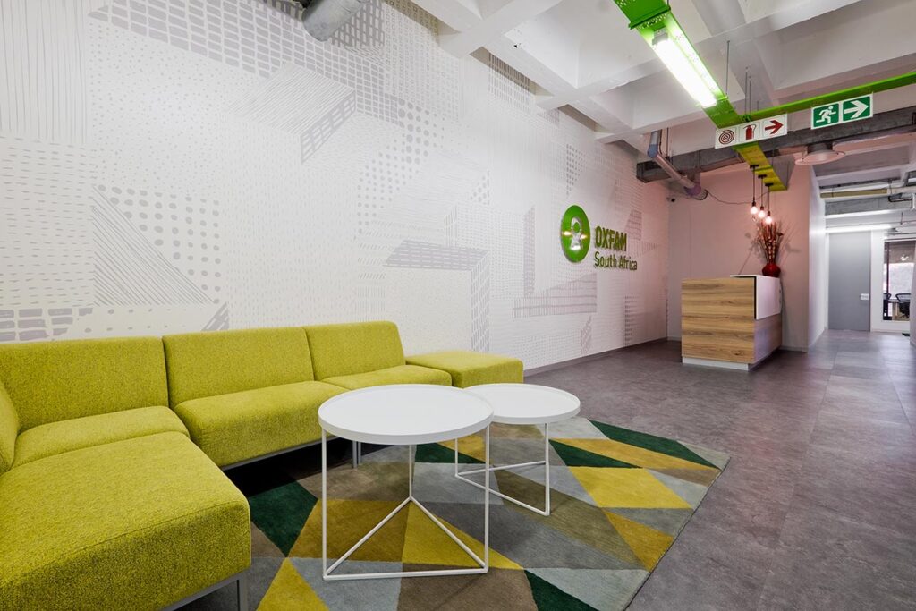 Oxfam commercial office reception area with signage and seating area with colorful branding and finishes and fit-out