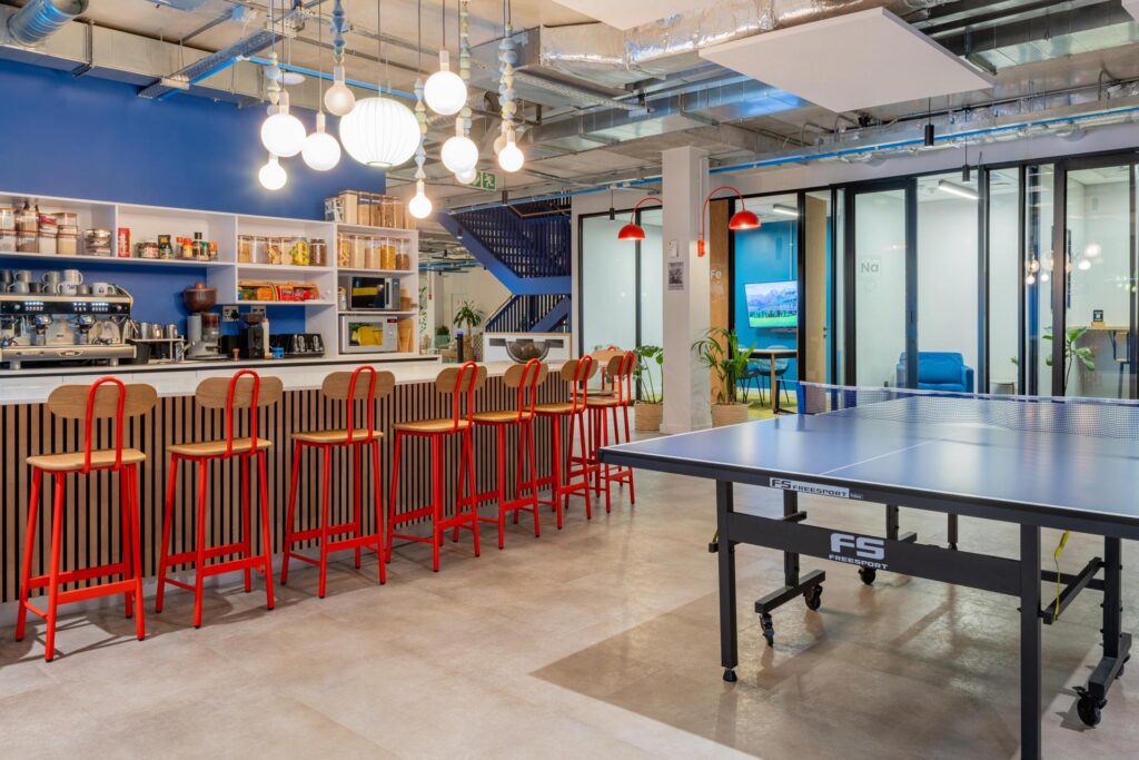 Red legged bar stools at office break area with games
