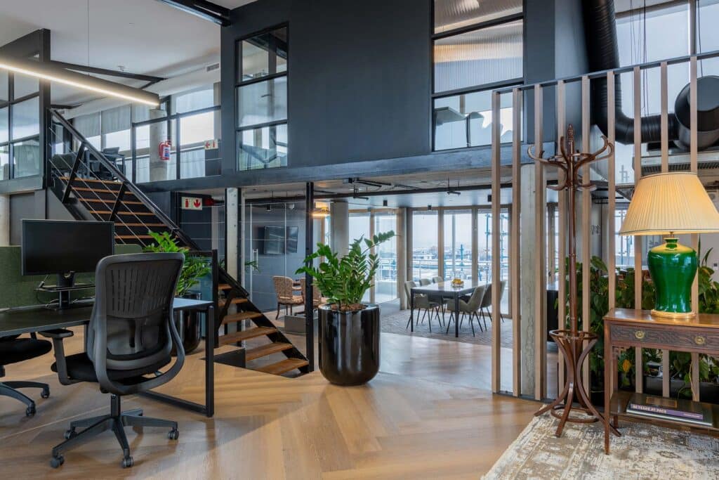 Contemporary financial services workspace with ergonomic office furniture, plants and industrial glass partitions and flexible office space